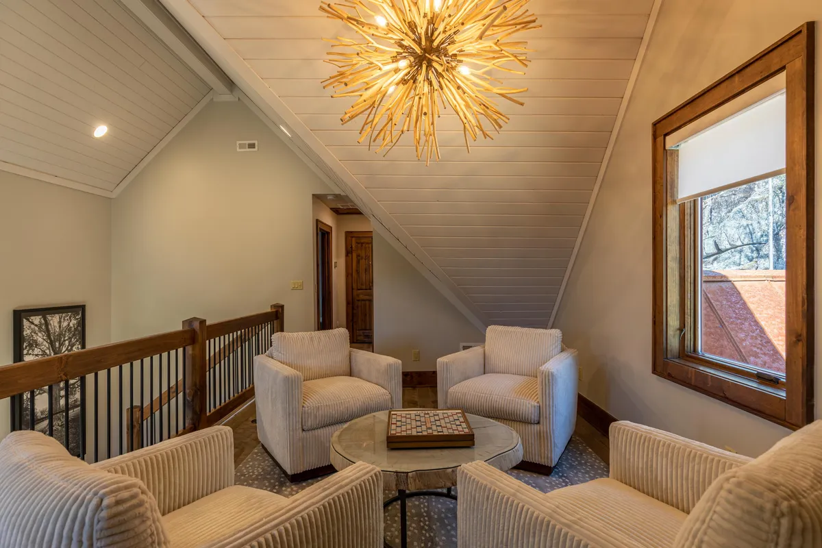 A relaxed, social interior featuring a unique light fixture above a comfortable, intimate seating arrangement. The textured walls and thoughtfully placed furniture create a cozy atmosphere ideal for conversation, reading, or games. The setting hints at versatility: perfect for quiet moments or lively socializing.