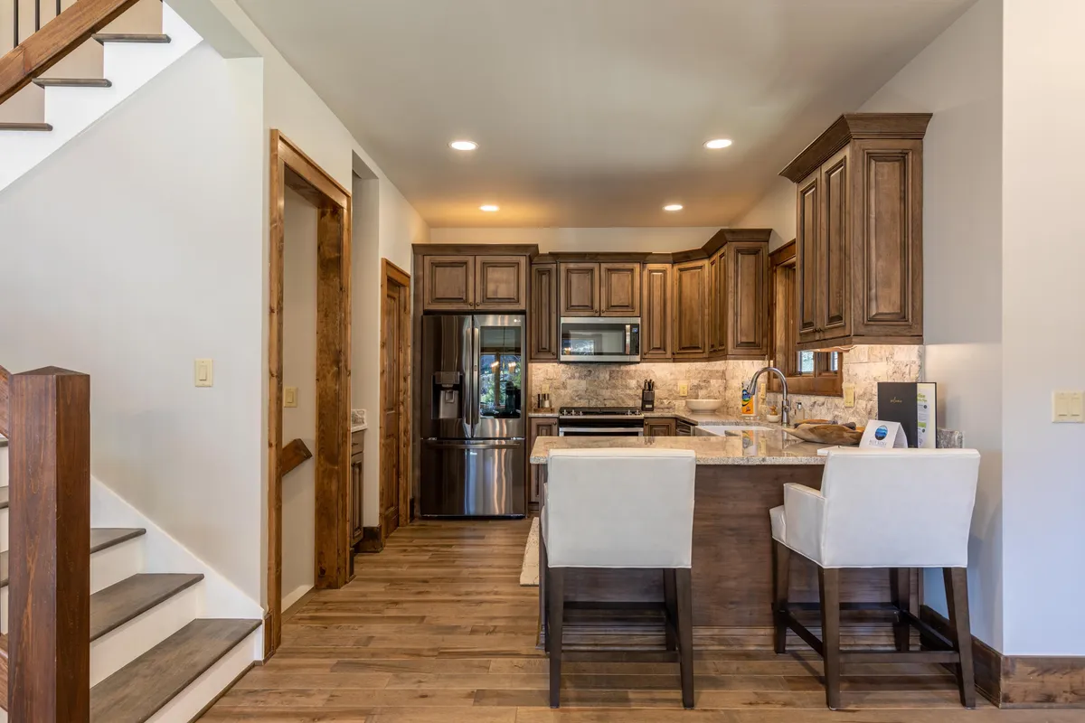 A modern kitchen with a prominent kitchen island, stainless steel appliances, and warm wood cabinetry. The space feels inviting and functional, perfectly suited for both everyday meal prep and entertaining guests. Subtle details hint at a space where culinary adventures unfold.